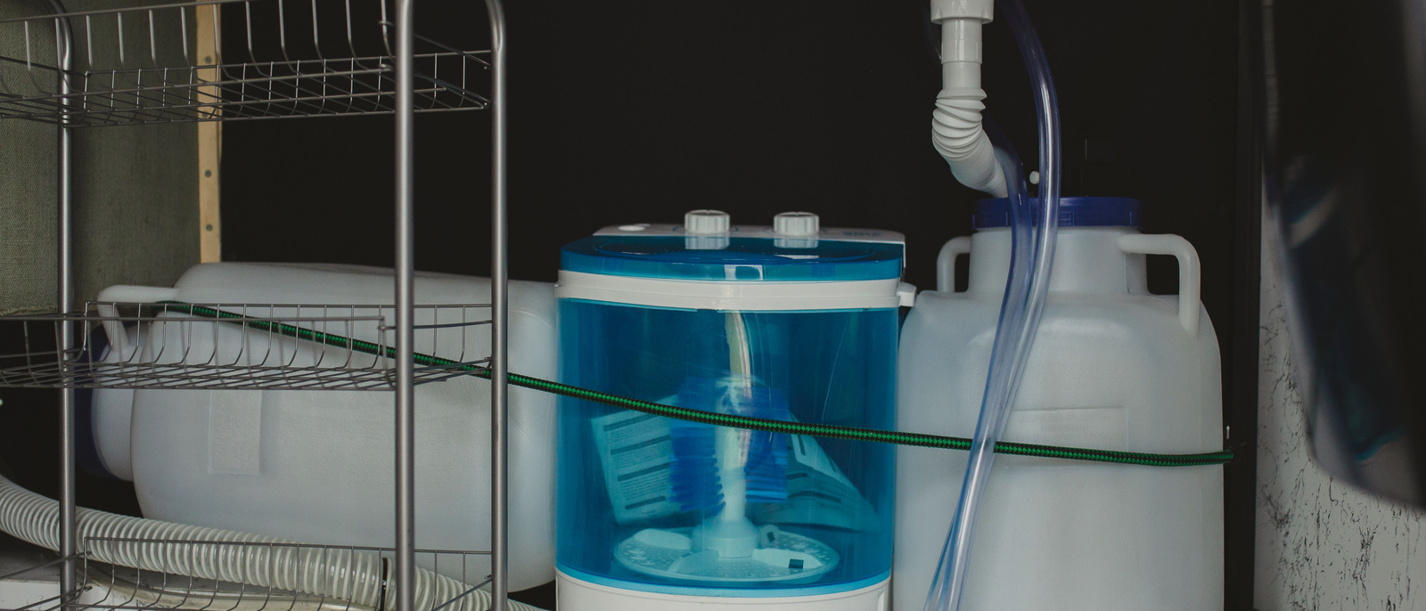 Blick unter eine Küchenspüle auf Siphon, Rohre und den dunklen Spalt dahinter