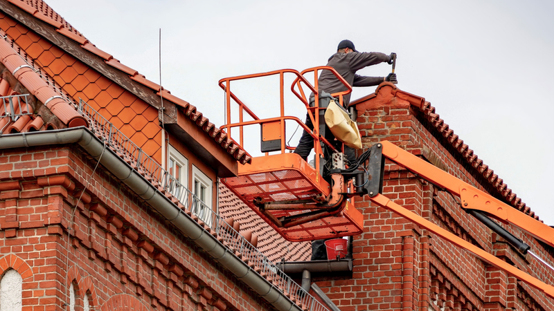 Dachdecker prüft angehobene Dachziegel und den Übergang zur Dachkante
